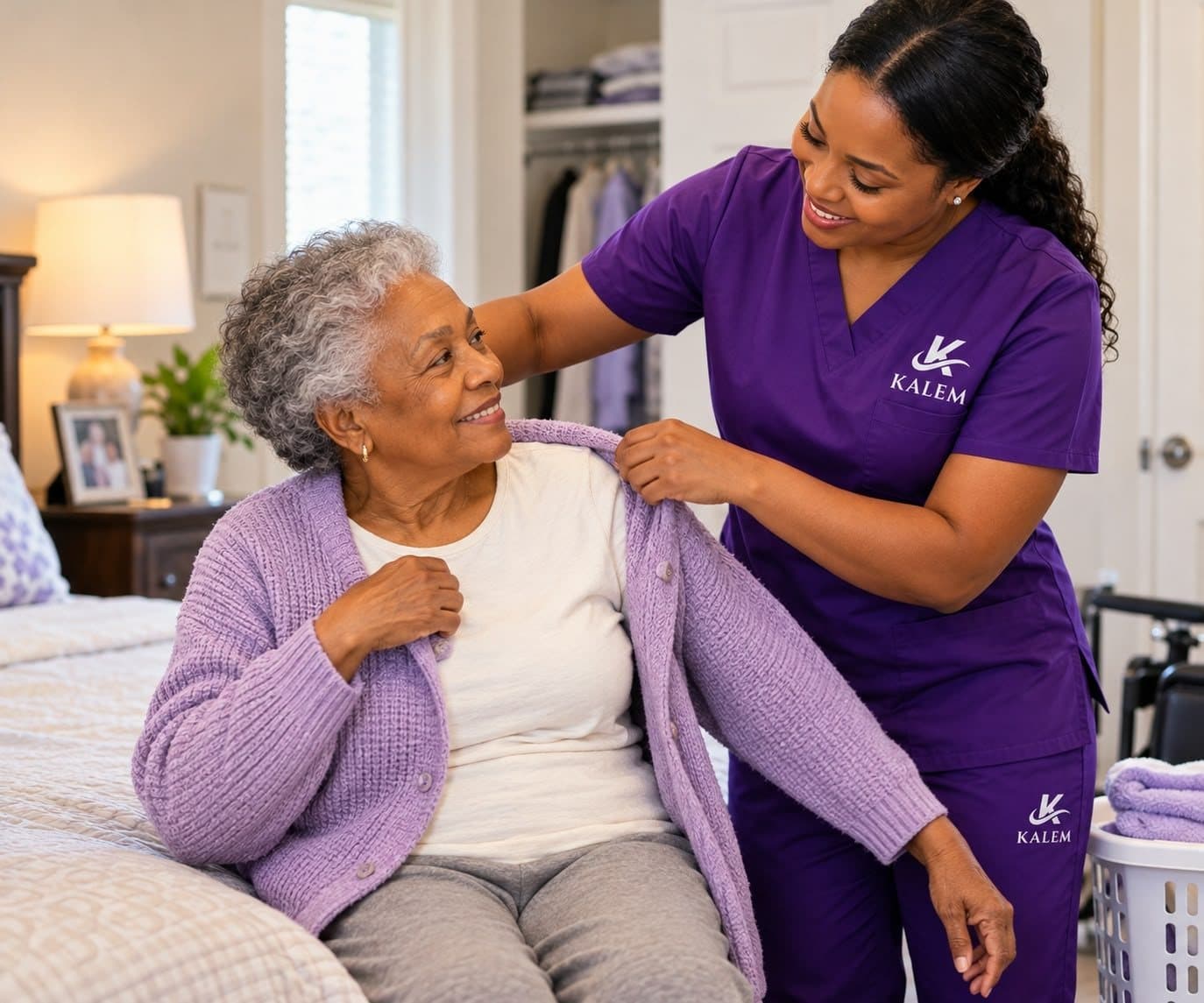 A KALEM caregiver helping an older woman put on her cardigan